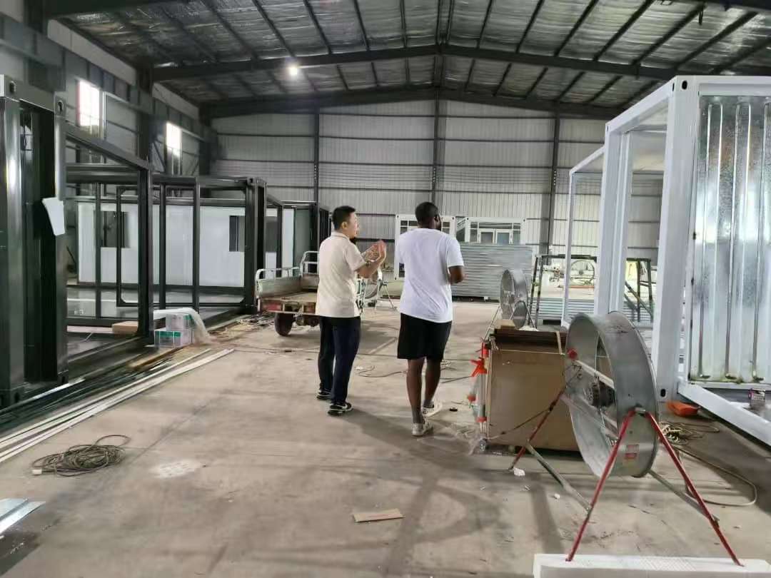 International buyer walking through Feeker factory with prefab container houses in production